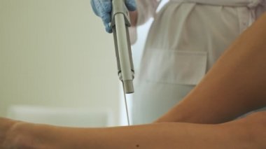 Profesyonel bir doktor-kozmetik uzmanının yakın çekimi güzellik salonundaki kadın müşteriye lazer tüy çıkarma prosedürü uyguluyor.