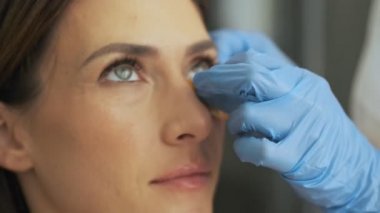 Profesyonel bir doktor-kozmetik uzmanının yakın çekim görüntüsü güzellik salonundaki kadın müşteriye yüz bakımı prosedürü uyguluyor.