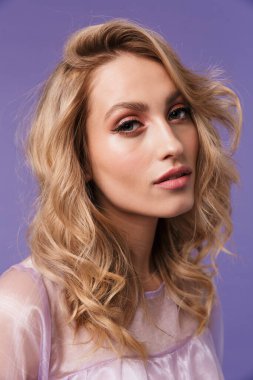 Mor arka planda izole edilmiş poz veren ve kameraya bakan güzel bir kadın resmi