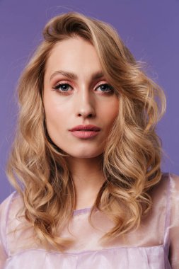 Mor arka planda izole edilmiş poz veren ve kameraya bakan güzel bir kadın resmi