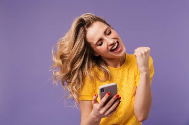 Heyecanlı güzel bir kadının, mor arka planda cep telefonunu kapalı tutarken kazandığı jestin görüntüsü
