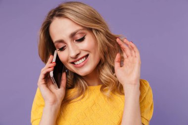 Mor arka planda izole bir şekilde cep telefonuyla konuşurken gülümseyen neşeli güzel bir kadın görüntüsü