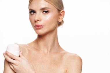 Beyaz arka planda izole edilmiş yüz kremiyle poz veren güzel üstsüz kadın resmi