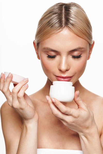 Image of beautiful pleased shirtless woman smelling face cream isolated over white background
