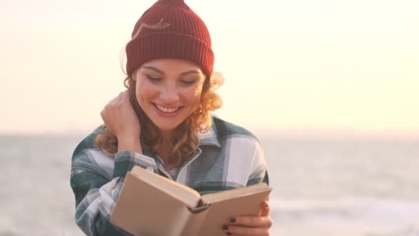 Açık Denizde Otururken Şapkalı Ekose Gömlekli Neşeli Sarışın Kadın Kitap — Stok video