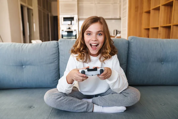 Uma menina sentada no sofá jogando um vídeo na sala de estar em casa. mão  de menina gamer animado segurando o joystick jogando jogo de console usando  um controlador sem fio.