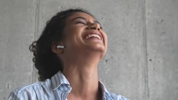 Μια Χαρούμενη Νεαρή Αφρικανή Ακουστικά Μιλάει Στο Τηλέφωνο Στο Σαλόνι — Αρχείο Βίντεο