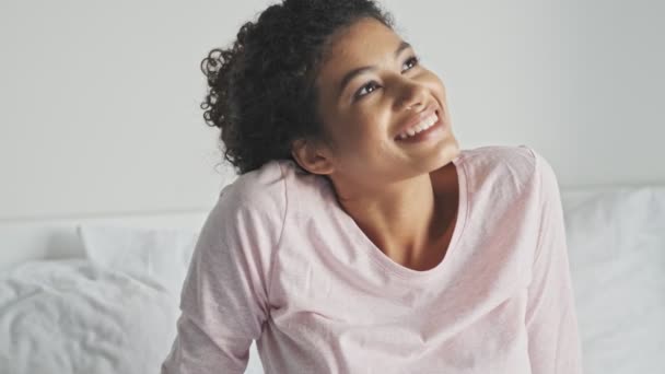 一位快乐的年轻非洲女人正坐在家里的床上 — 图库视频影像