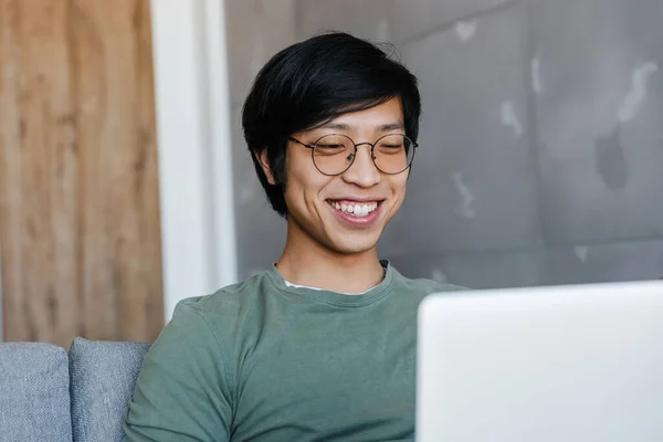 Imagen Joven Hombre Asiático Guapo Usando Anteojos Usando Portátil Mientras —  Fotos de Stock