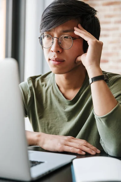 Imagen Joven Hombre Asiático Guapo Usando Anteojos Usando Portátil Mientras —  Fotos de Stock