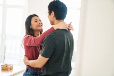 Güzel mutlu Asyalı çift mutfakta beklerken kucaklaşıyorlar.