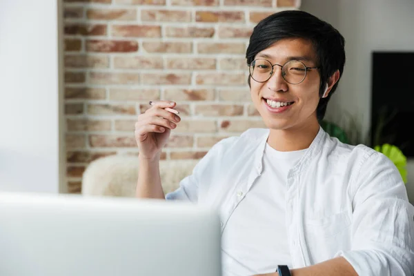Image Handsome Young Asian Man Wearing Earphones Using Laptop While — Stock Photo, Image