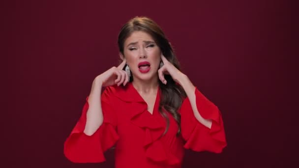 Kırmızı Elbise Giyen Duygusal Genç Bir Kadın Parmaklarıyla Kulaklarını Kapatıyor — Stok video
