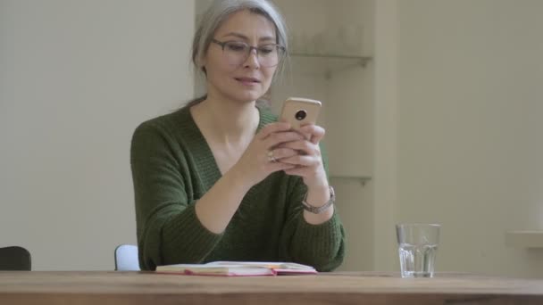 Skoncentrowany Atrakcyjny Dojrzała Kobieta Długimi Siwymi Włosami Okularach Pomocą Smartfona — Wideo stockowe