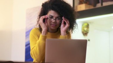 Sakin Afrikalı çekici bir kadın gözlük takıyor ve dizüstü bilgisayar kullanıyor.