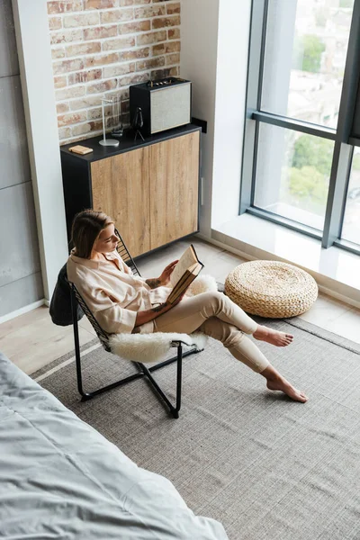 Oturma Odasındaki Koltukta Otururken Şık Pijamalarıyla Kitap Okuyan Genç Düşünceli — Stok fotoğraf