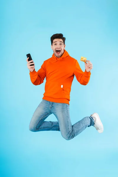 Portrait Cheerful Young Man Wearing Hoodie Jumping Isolated Blue Background — Stock Photo, Image