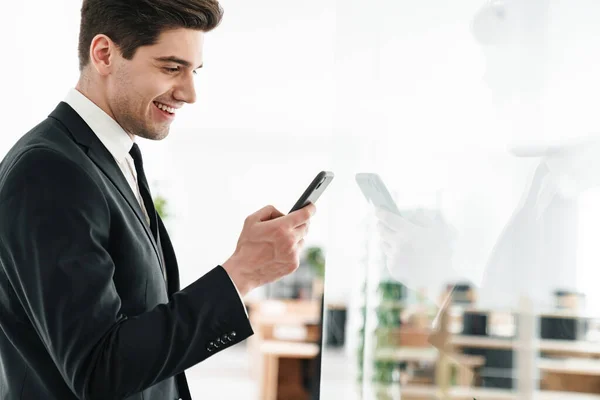 Imagen Joven Hombre Negocios Sonriente Con Traje Negro Usando Teléfono — Foto de Stock