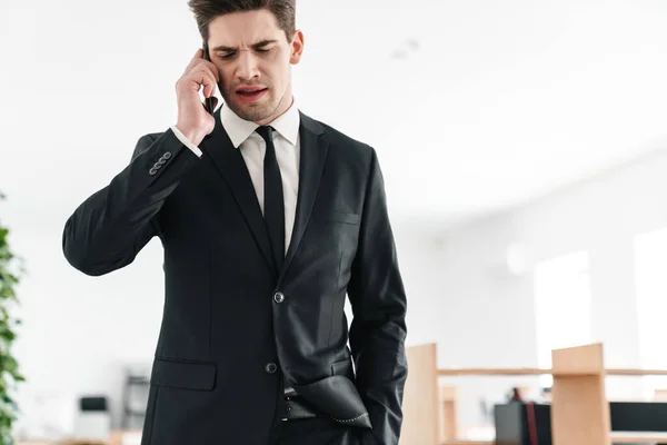 Ofiste Siyah Takım Elbiseli Cep Telefonuyla Konuşan Hoşnutsuz Genç Adamının — Stok fotoğraf