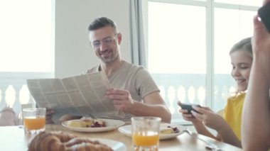 İyi görünümlü genç bir aile sabah kahvaltısını evde yerken mutfakta vakit geçiriyor.