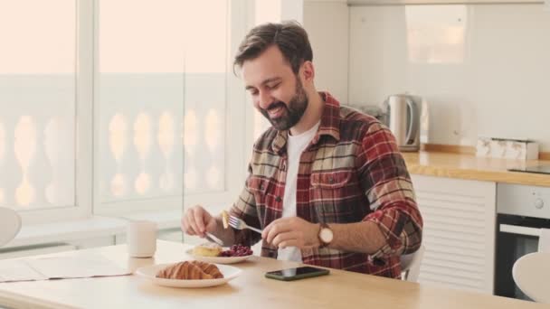 Komea Nuori Positiivinen Onnellinen Parrakas Mies Keittiössä Sisätiloissa Kotona Aamiaisella — kuvapankkivideo