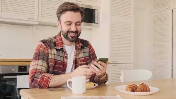 Bonito Jovem Homem Barbudo Satisfeito Cozinha Casa Tomando Café Manhã — Vídeo de Stock