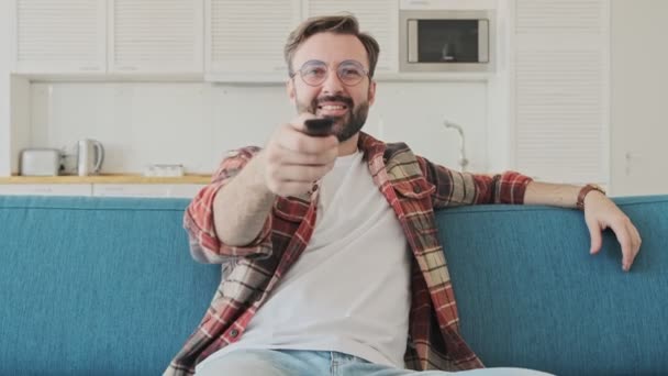 Bonito Jovem Otimista Barbudo Homem Dentro Casa Sentado Sofá Enquanto — Vídeo de Stock