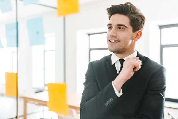 Imagem Jovem Empresário Satisfeito Vestindo Terno Sorrindo Usando Adesivos Enquanto — Fotografia de Stock