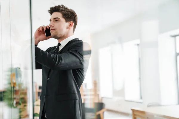 사무실에서 일하는 사업가가 양복을 휴대폰으로 얘기하는 — 스톡 사진