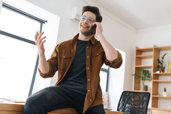 Bild Stilig Glad Ung Man Ler Och Pratar Mobiltelefon När — Stockfoto