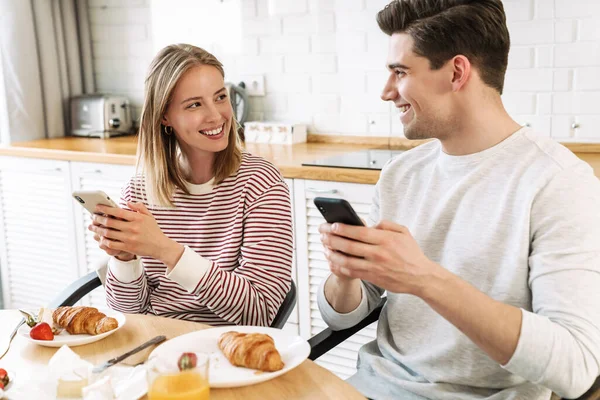 Retrato Pareja Sonriente Usando Teléfonos Inteligentes Hablando Mientras Desayunaba Acogedora — Foto de Stock