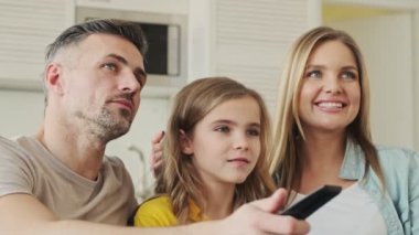 Çekici genç bir aile evde televizyon izlerken patlamış mısır yiyor.