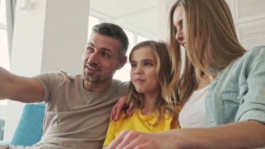 Genç ve güzel bir aile evde birlikte televizyon izlerken patlamış mısır yiyor.