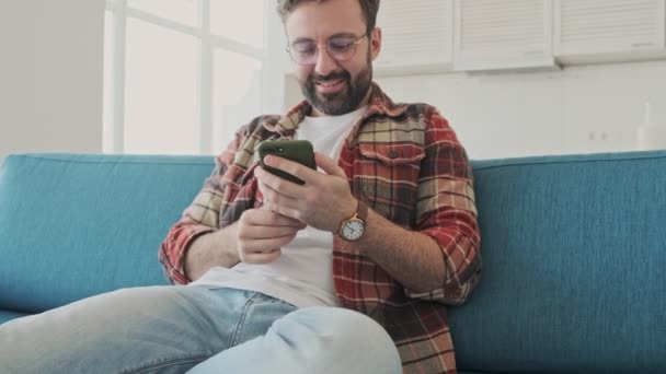 Bonito Jovem Positivo Barbudo Feliz Homem Dentro Casa Sentado Sofá — Vídeo de Stock