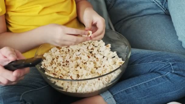 一个快乐的年轻家庭一边在客厅看电视一边吃爆米花 — 图库视频影像