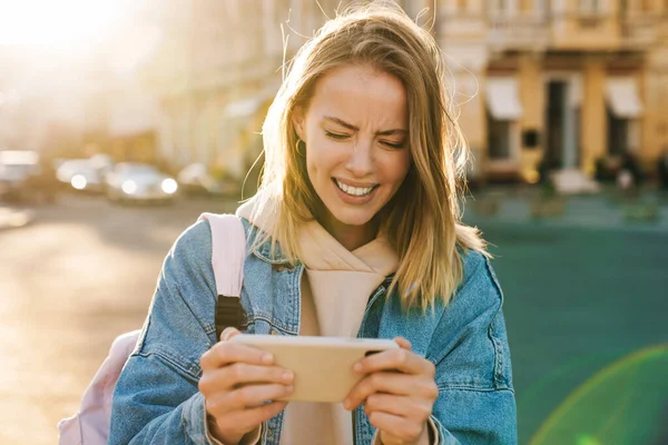 Gyönyörű Zavaros Fiatal Szőke Visel Farmer Kabát Séta Városban Mobiltelefon — Stock Fotó