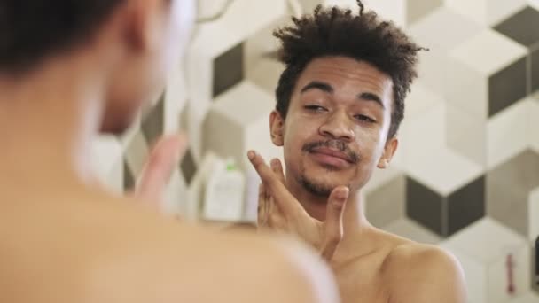 Fiatal Jóképű Pozitív Afrikai Srác Vigyáz Bőrére Arckrémmel Beltéri Tükör — Stock videók