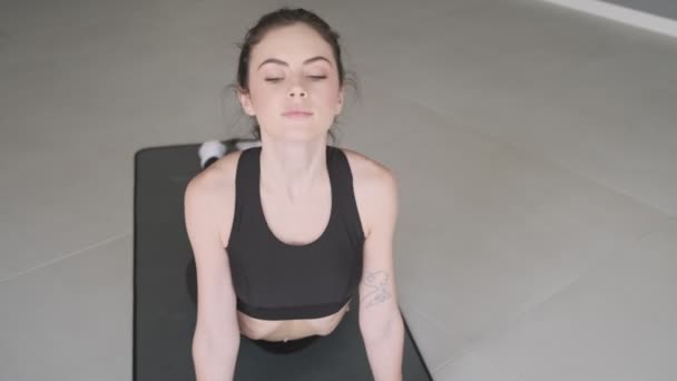 Attraktiv Ung Kvinna Stretchar Sin Rygg Gör Yogaövningar Mattan Grå — Stockvideo