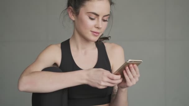 운동복을 아침에 스튜디오에서 훈련을 스마트폰을 사용하는 모습을 가까이 수있다 — 비디오