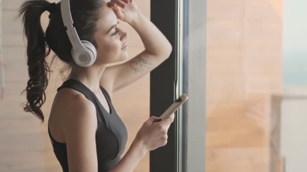 Una Vista Lateral Una Joven Deportista Chándal Negro Está Escuchando — Vídeos de Stock