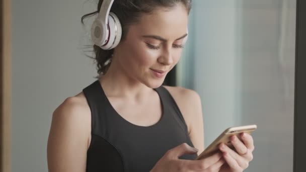 Μια Θετική Ικανοποιημένη Νεαρή Γυναίκα Μαύρη Φόρμα Ακουστικά Ακούει Μουσική — Αρχείο Βίντεο