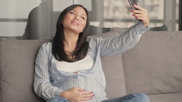 Una Bonita Embarazada Asiática Está Tomando Selfie Teléfono Sentado Sofá — Vídeo de stock