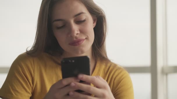 Μια Όμορφη Εστιασμένη Νεαρή Γυναίκα Πληκτρολογεί Κάτι Στο Smartphone Της — Αρχείο Βίντεο