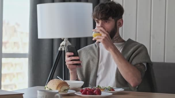 Joven Hipster Encantador Está Utilizando Teléfono Inteligente Durante Desayuno Sentado — Vídeos de Stock