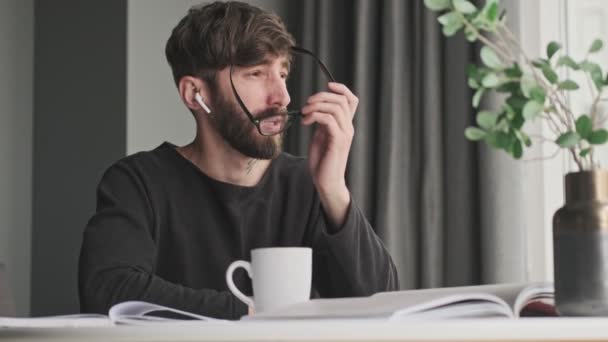 Jovem Sério Hipster Com Fones Ouvido Usando Óculos Está Pensando — Vídeo de Stock