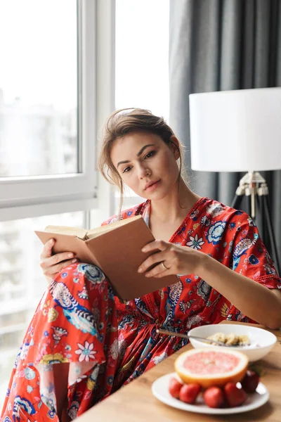 Zdjęcie Młodej Zadowolonej Stylowej Kobiety Czytającej Książkę Podczas Śniadania Przytulnym — Zdjęcie stockowe