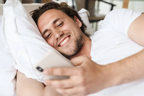 Sonriente Joven Acostado Una Almohada Cama Usando Teléfono Móvil — Foto de Stock