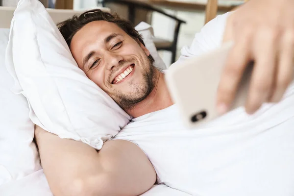 Sonriente Joven Acostado Una Almohada Cama Tomando Una Selfie —  Fotos de Stock