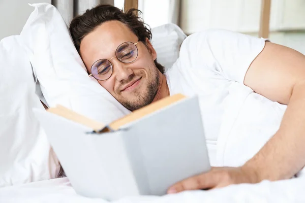 Jeune Homme Souriant Allongé Sur Oreiller Lit Lisant Livre — Photo