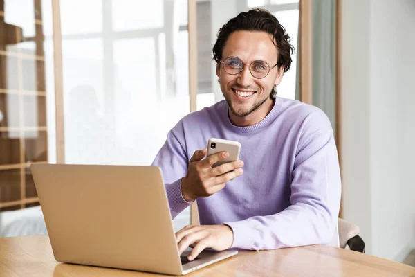 Attractive Cheerful Young Man Sitting Kitchen Table Working Laptop Computer — Stock Photo, Image